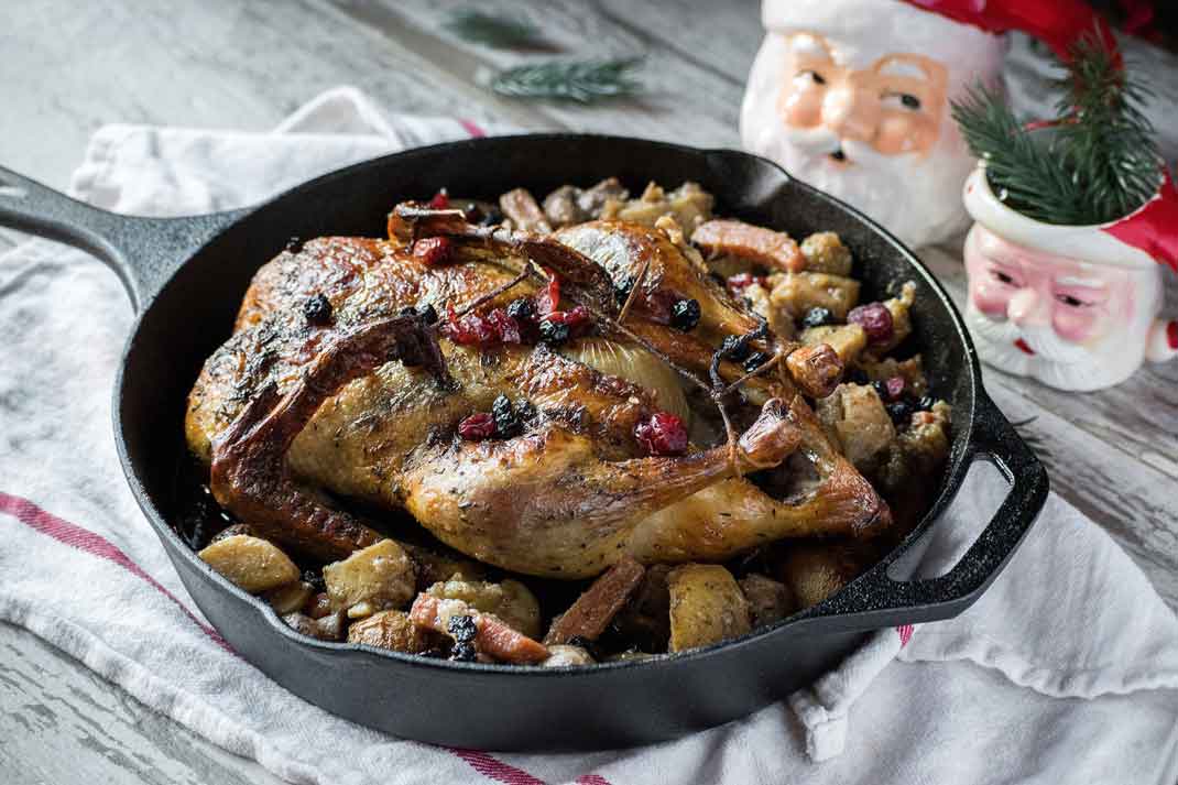 holiday roast baked duck on roasted vegetables in cast iron pan with cranberries | Hunting Magazine