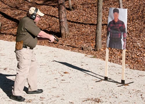 Aim the pistol at the floor right in front of the target, and use a loud ordering tone.