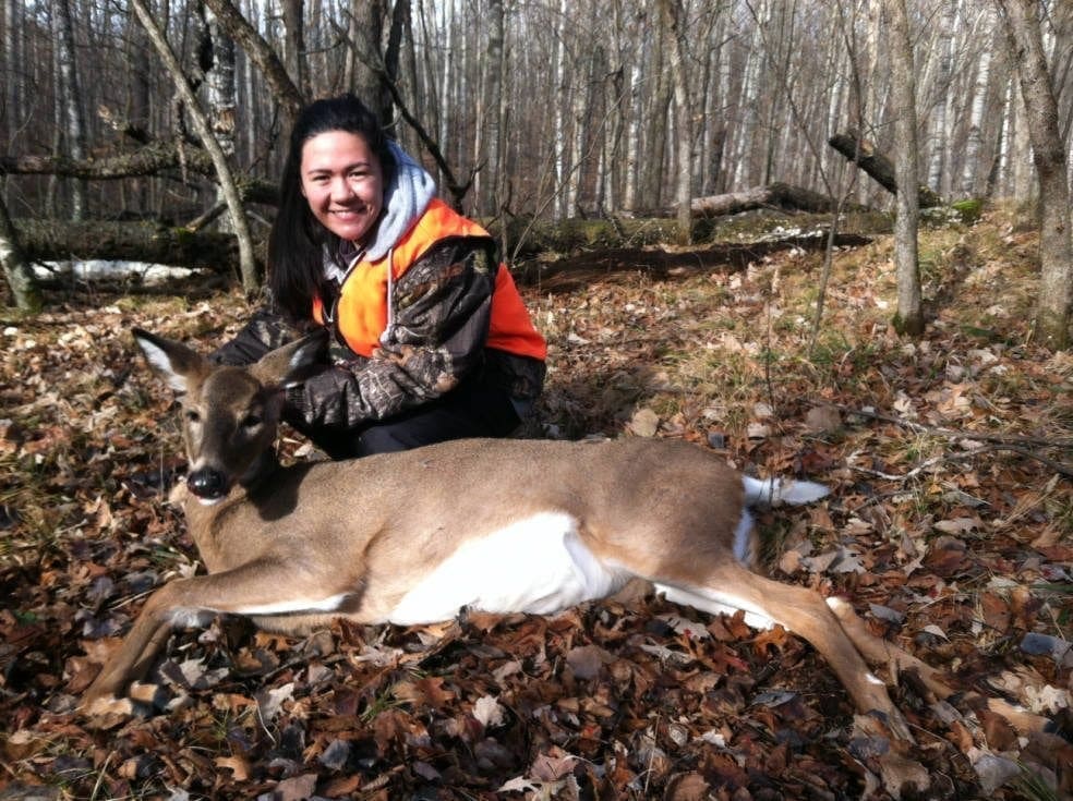 Young female hunter poses with harvested White-tailed deer taken during the Minnesota firearms deer season.